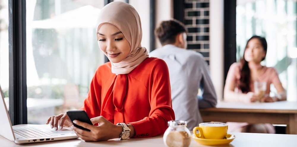 Kvinde i hijab arbejder på sit CV på en hip cafe.