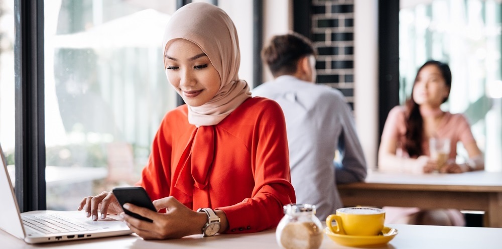 Woman in hijab is working on her CV in a hip cafe.