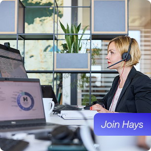 Medarbejder sidder ved sin arbejdsplads og taler i telefon med headset