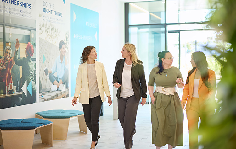 Fire kolleger går side om side gennem foyeren.