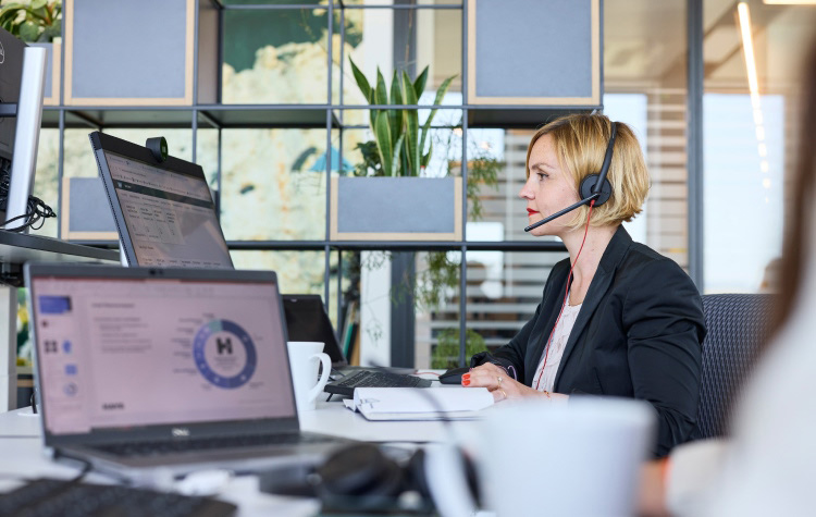 Employee sitting at her computer and talking on the phone with a headset