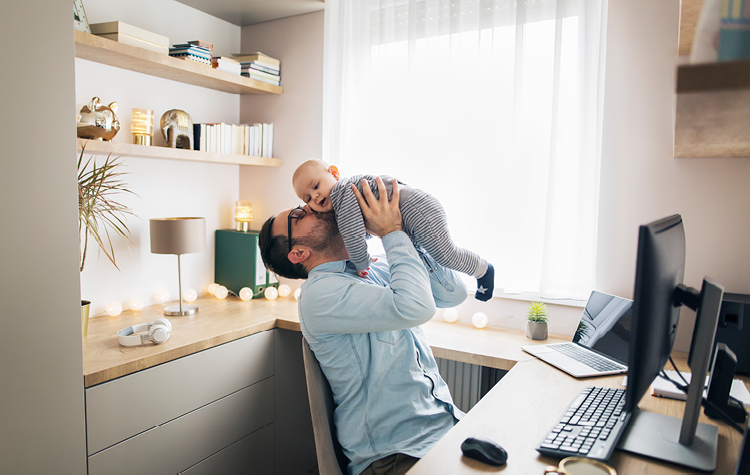 Mand arbejder hjemmefra mens han passer sin baby
